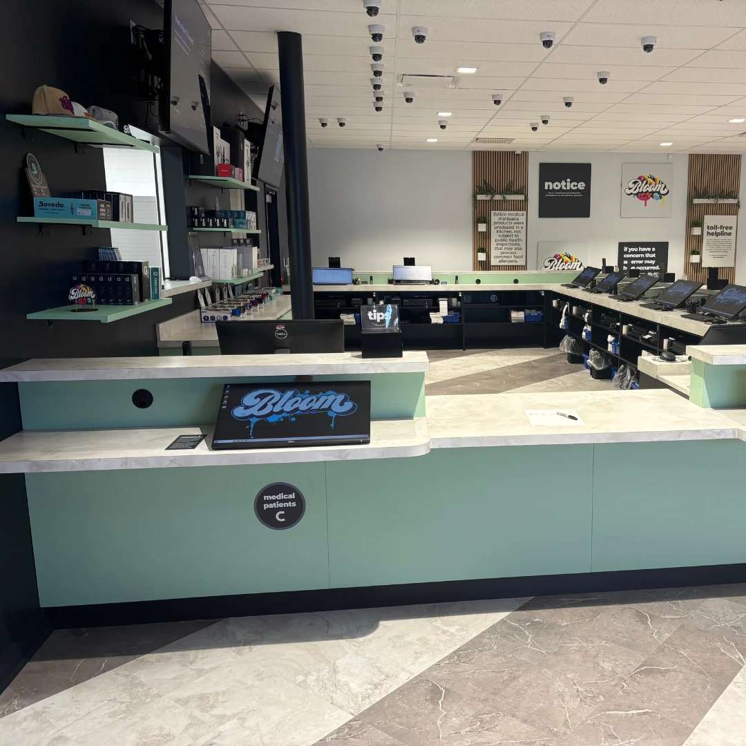 Bloom south columbus dispensary a modern retail store interior with mint green counters, digital displays, and neatly arranged products on shelves under bright lighting.