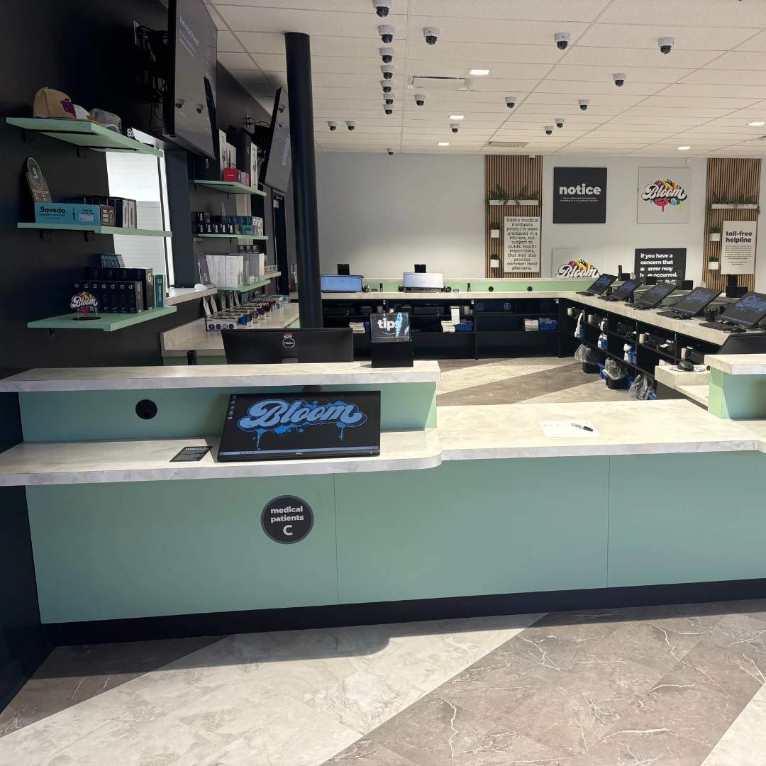 Bloom south columbus dispensary a modern retail store interior with mint green counters, digital displays, and neatly arranged products on shelves under bright lighting.