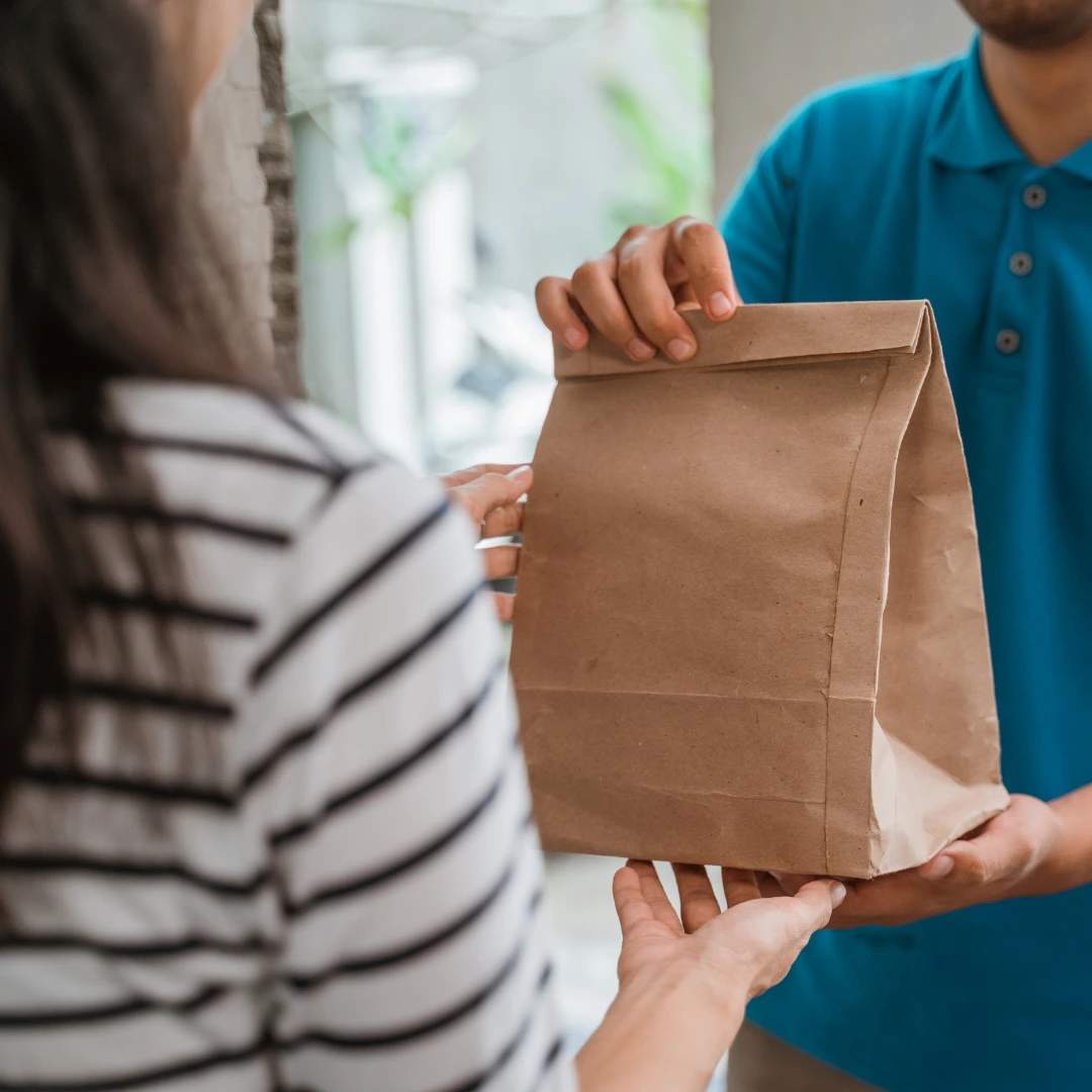 man delivering cannabis products in ohio in a clear paper bag to a women