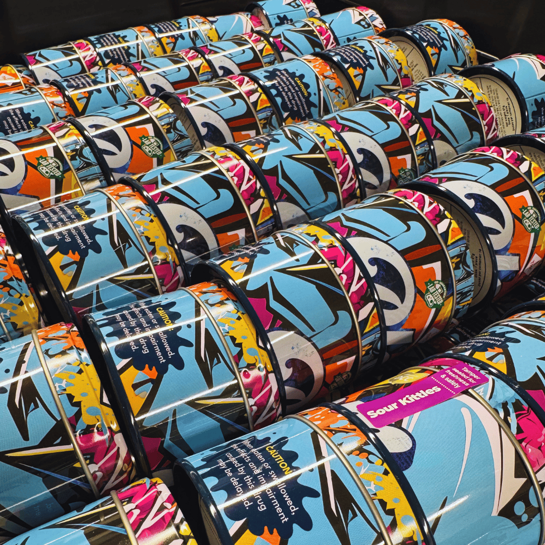 Rows of colorful, patterned tins with abstract designs, labeled "Sour Kicks," arranged neatly on a shelf.